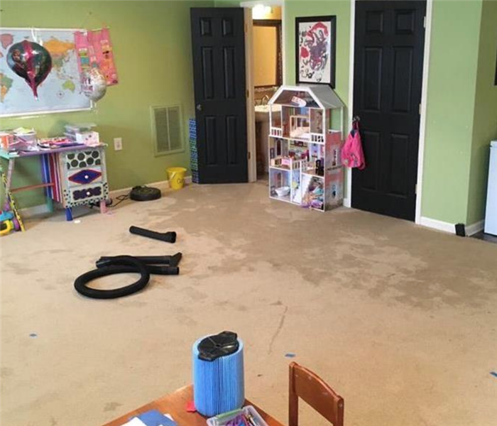 A playroom with a large water stain on the carpet