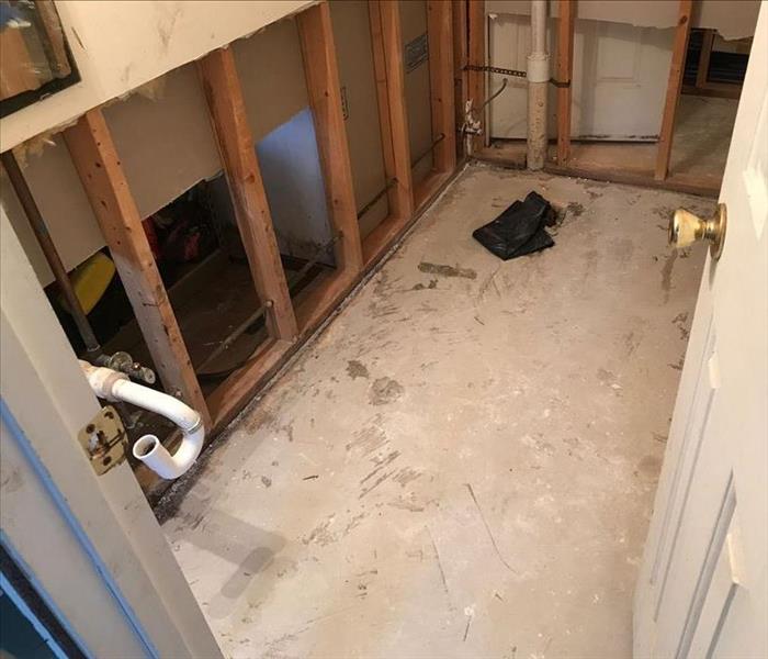 A bathroom with flooring, walls, and the toilet removed.