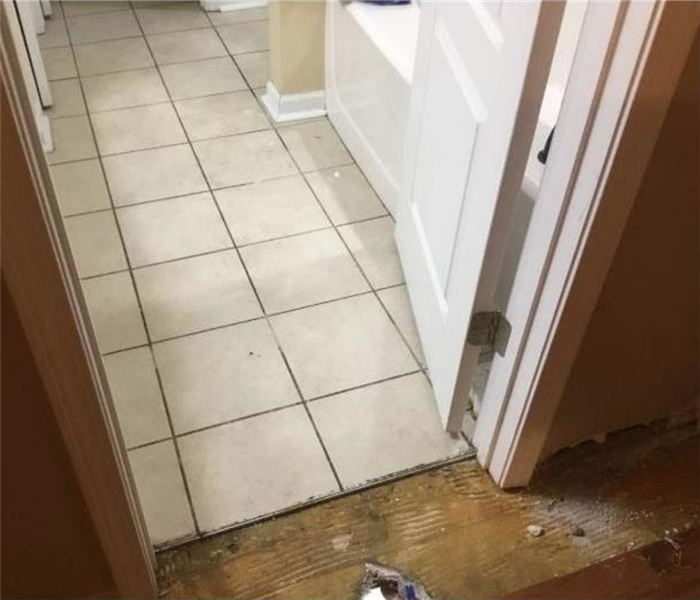 Tile floor covered in water and carpet ripped up