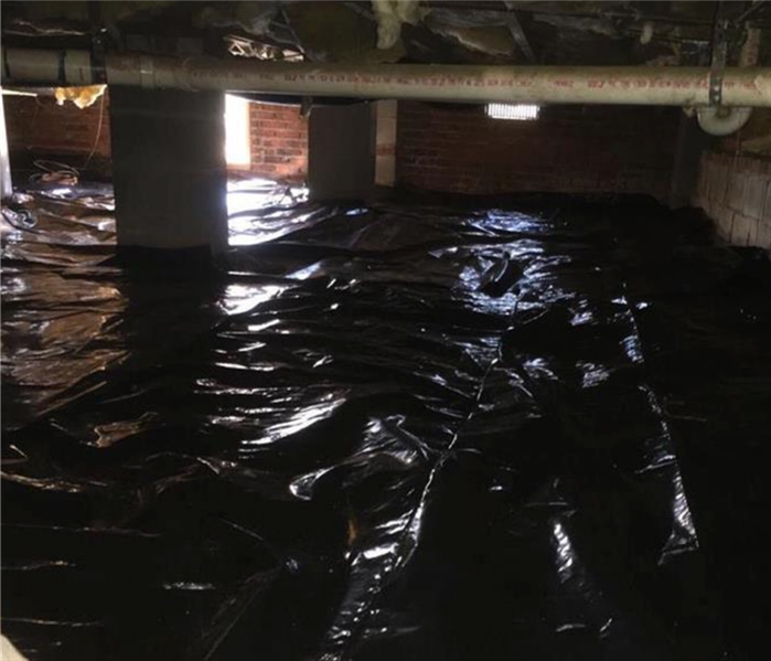 The entire crawl space covered in black tarp post restoration